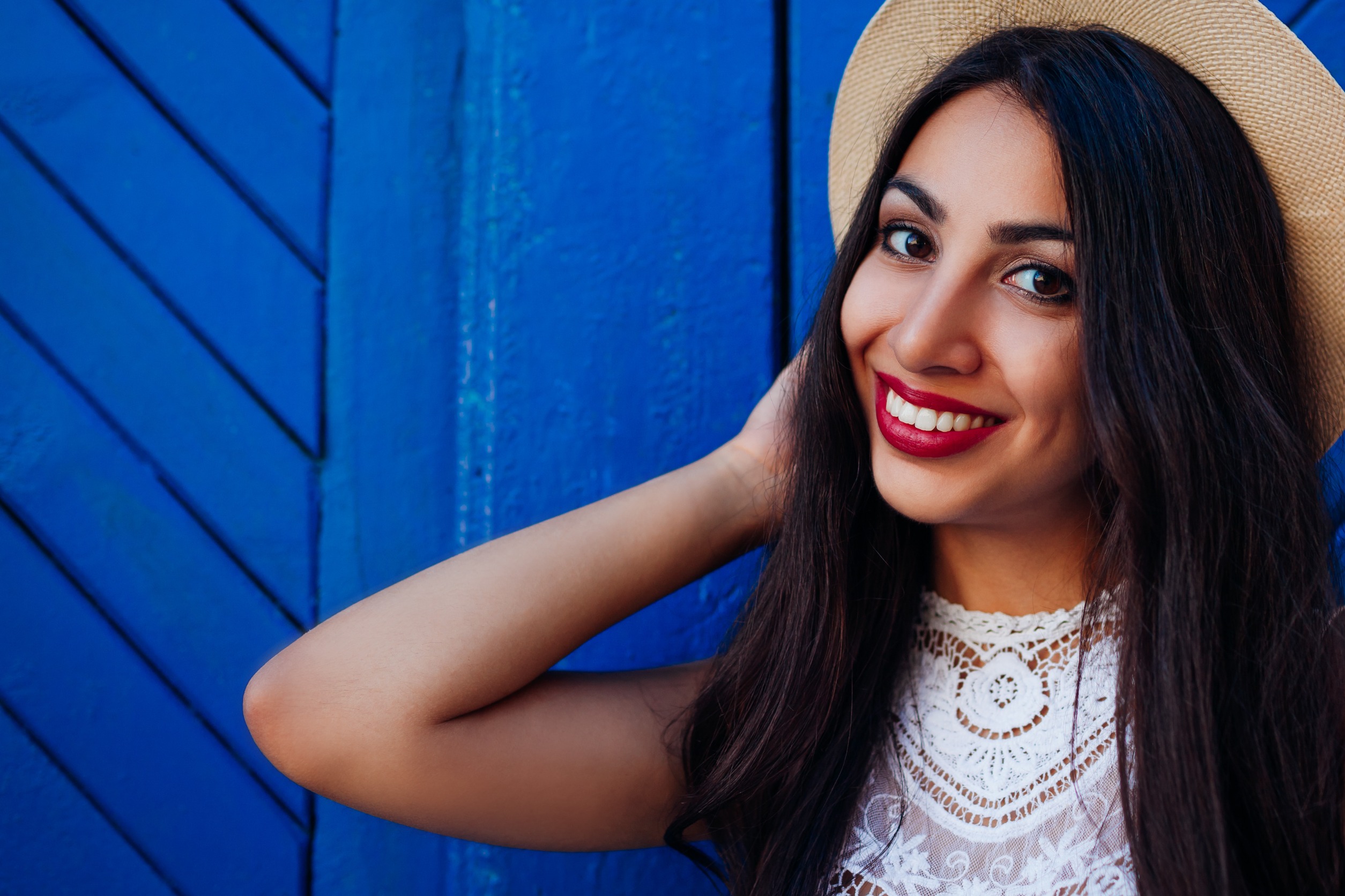 Image of a smiling woman wearing a hat and standing in front of a blue wall. Learn how EMDR therapy in Denver, CO can provide you with rapid relief if you are struggling with anxiety.
